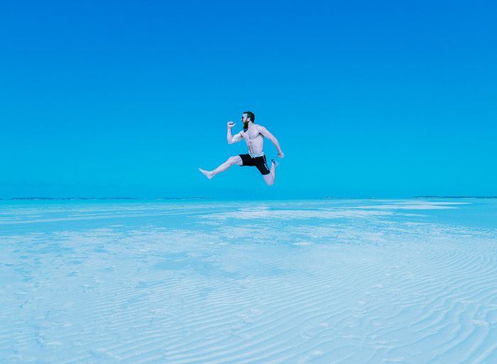 Guy jumping as high as he cn over a large body of water